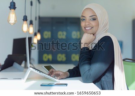 Young muslim African American business woman as a leader at work. Teamwork and multiethnic concept. Happy successful business leader working at her office, looking and smiling into camera.