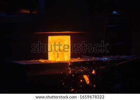 close-up picture of hot steel manual forging process with big mechanical hammer machine