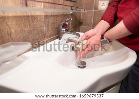 Man is washing his hands with a soap in a bathroom. Washing hands with soap under the faucet with water.
