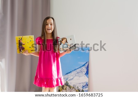A happy little girl holds canvas at home