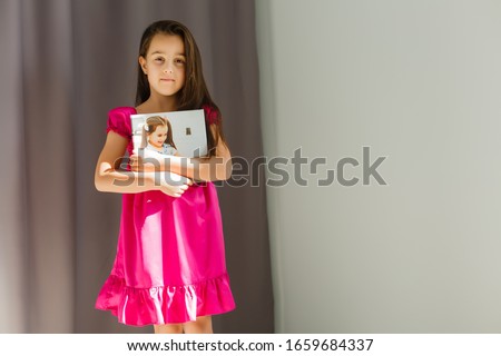 A happy little girl holds canvas at home