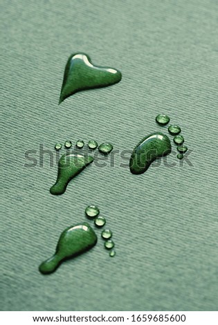 Water footprints from drops lead to the heart, on a green background. Water footprints. Drops of water that look like bare footprints. Foots shaped by water drop. 