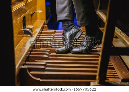 The musician pushes his feet on the pedals of the organ