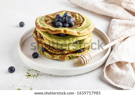 matcha pancakes on a white background with blueberries and honey vegan food Royalty-Free Stock Photo #1659717985