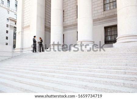 Two well dressed professionals in discussion on the exterior steps of a courthouse. Could be lawyers, business people etc. Royalty-Free Stock Photo #1659734719