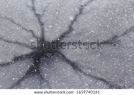 Dark cracks on thin ice. Background image. Dangerous ice. Thin spring ice.