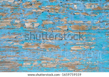 Flaking paint on wood with complimentary colours of sky blue and yellow brown. Rustic, crusty texture producing a random linear pattern like tree bark. Landscape orientation. Royalty-Free Stock Photo #1659759559