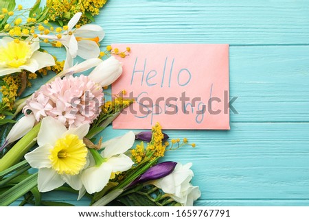 Pink card with words HELLO SPRING and fresh flowers on light blue wooden table, flat lay Royalty-Free Stock Photo #1659767791