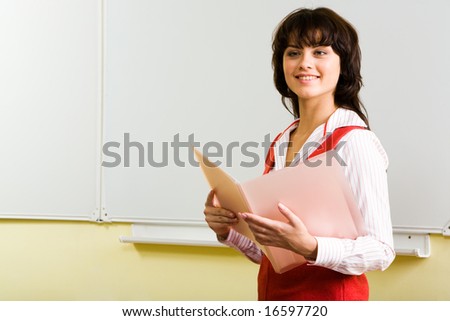 Photo of smiling teenager with folder in hands and whiteboard on background