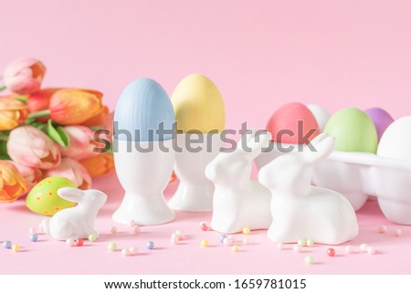 Easter holiday decorations on pink background with eggs and bunnies, festive greeting card