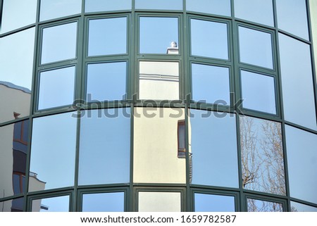 Glass transparent windows on the facade of a modern office or commercial building. Building in the center of a big city reflect the blue sky.