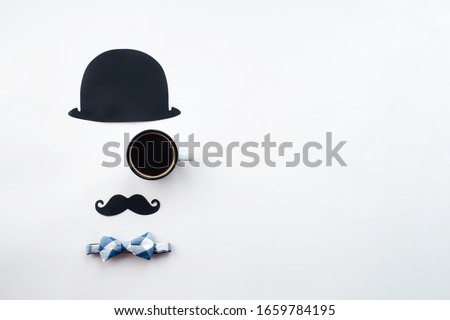 
Holiday concept Father's Day. Flatlay Hat, coffee mug, bow-tie and funny black mustache on a white background. Copy space for text.