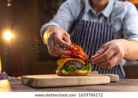 Close up of a female chef, preparing a tasty, fresh, delicious hamburger in a restaurant or pub