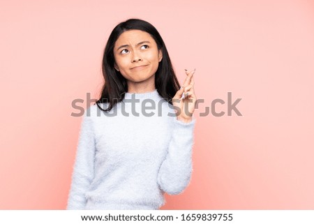 Teenager Chinese woman isolated on pink background with fingers crossing and wishing the best