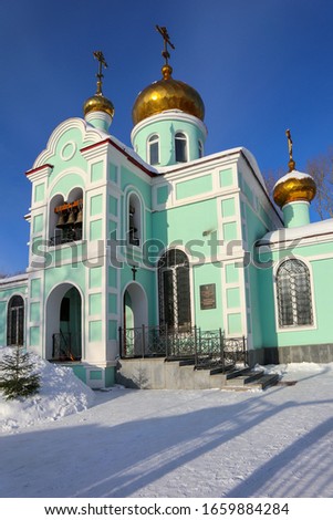 Church of Saint Blessed Xenia of St. Petersburg in Yekaterinburg city, Russia. Beautiful Russian temple with golden domes and crosses on a background of blue sky in a winter sunny day.