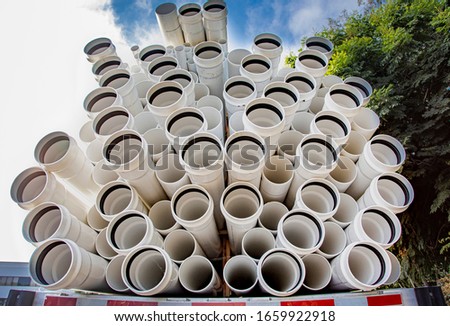 White plastic irrigation pipes stacked on the back of a truck 