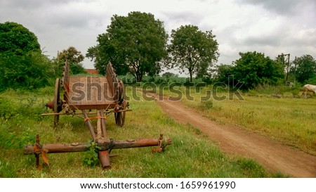 Some Photos of Old indian wooden bullock cart in green farm. Vintage style wooden bullock cart in rusty brown colour with pleasant sky.