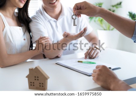 Real estate agency giving house key to customer after contract is completed.