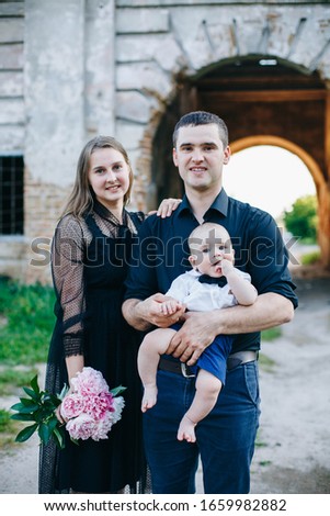family portrait of mom and dad with son. mom with a bouquet of peonies in a black dress. family love and respect