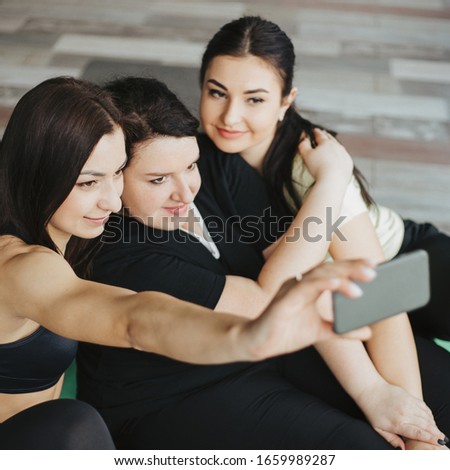 Photography, technology, friendship, fun. Woman taking picture of her friend using mobile phone. Three females having fun together