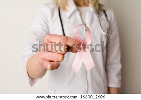 Woman doctor holding a pink ribbon in her hands - image