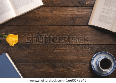 Open books, cup of coffee, rose, on wooden background. Flat lay, top view, copy space.