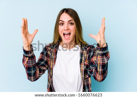 Young caucasian woman isolated on blue background receiving a pleasant surprise, excited and raising hands.