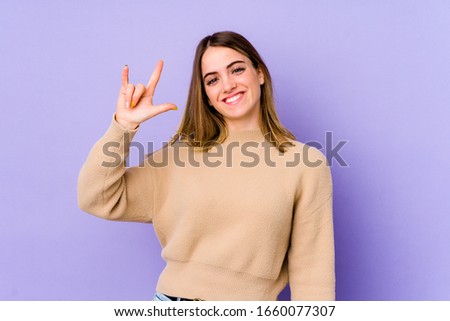Young caucasian woman isolated on purple background showing a horns gesture as a revolution concept.