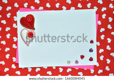 Greeting card decorated with multi-colored large and small hearts on a red fabric background