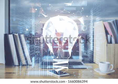 Computer on desktop in office with bulb icon hologram. Multi exposure. Concept of idea.