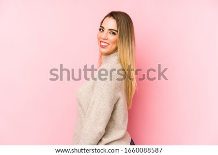 Middle age woman over isolated background looks aside smiling, cheerful and pleasant.