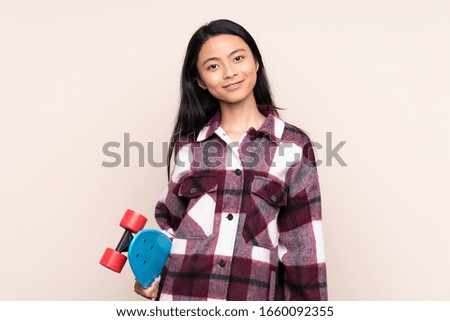 Teenager Chinese girl isolated on beige background with a skate
