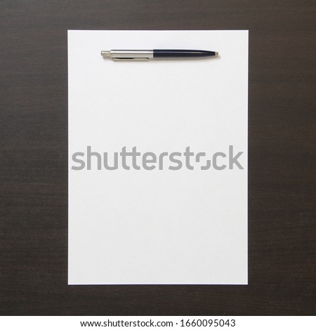 Template of white paper with pen on dark wenge color wooden background. Concept of business plan and strategy. Stock photo with empty space for text and design.
