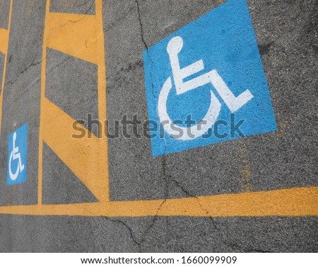 blue and white sign on the asphalt indicating a parking for disabled people
