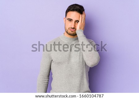 Young caucasian man isolated on purple background tired and very sleepy keeping hand on head.