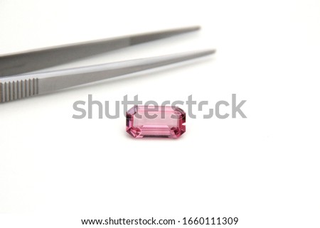 Gemstone Pink Sapphire Spinel tourmaline facet rectangular shape with tweetzer on white background with selective focus