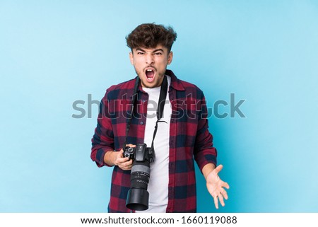 Young arab photographer man isolated screaming very angry and aggressive.