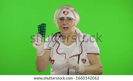 Portrait of elderly caucasian female doctor talking to camera with tablet blisters. Female nurse. Virus protection. Pandemic. Coronavirus. Covid-19. Green screen. Chroma key