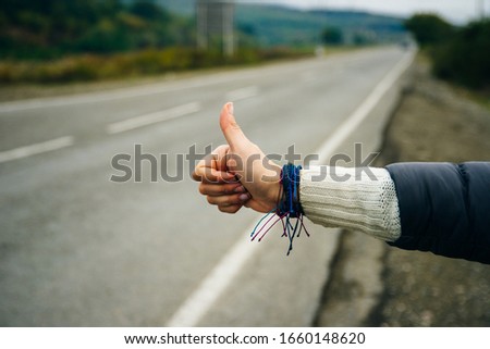 Woman's hand in hitch hiking sign to ask for a car as passenger