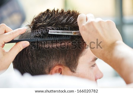 Hairdresser making haircut to young man at beauty parlour Royalty-Free Stock Photo #166020782
