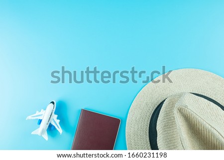 Top view Hat, Passport and Plane model on blue background with copy space for text. Travel and Vacation concept