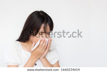 asian girl has a cold and sneeze on tissue paper