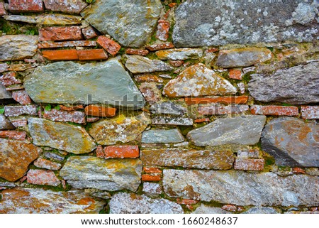 Closeup of an old, ancient wall made of river stones and bricks. Architecture background of regular rocks, antique bricks, from a historical house. Beautiful macro composition in Tuscany, Italy.