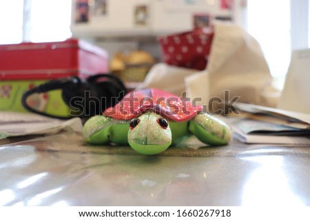 Toy turtle hiding by a set of keys on the kitchen table top