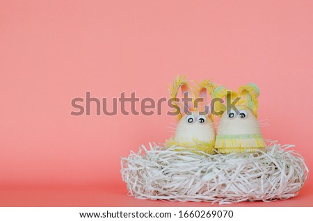 aeggs decorate as bunny dressing put on messy cutting paper nest with pink background. Cute creative photo concept.
