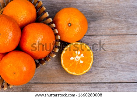 Fresh organic tangerine orange fruits in wooden basket and half slice  isolated on rustic wood table background.