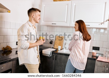 smiling man enjoying watching how his wife doing household chores, washing dishes. close up photo