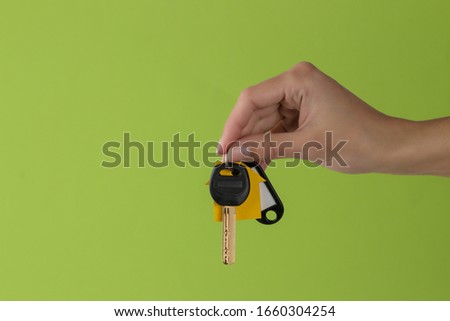 Home purchase concept. Keys with a keychain house in hand on a green background