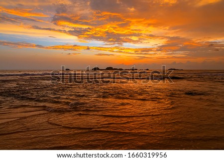 Dramatic sunset sky with red yellow clouds over ocean in Sri Lanka island