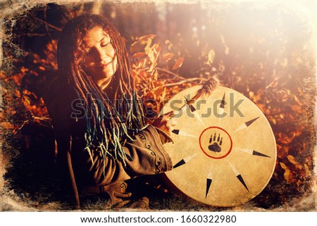 beautiful shamanic girl playing on shaman frame drum in the nature, old photo effect.